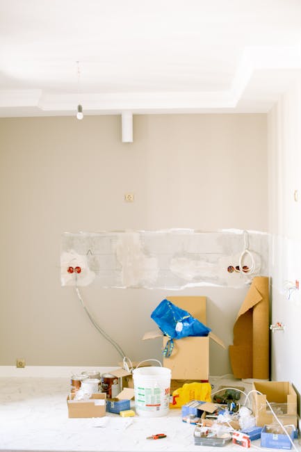 Inside a room during a home relocation process, showing a partially finished interior wall with exposed electrical outlets and wiring, and a large horizontal patch of joint compound. In the foreground